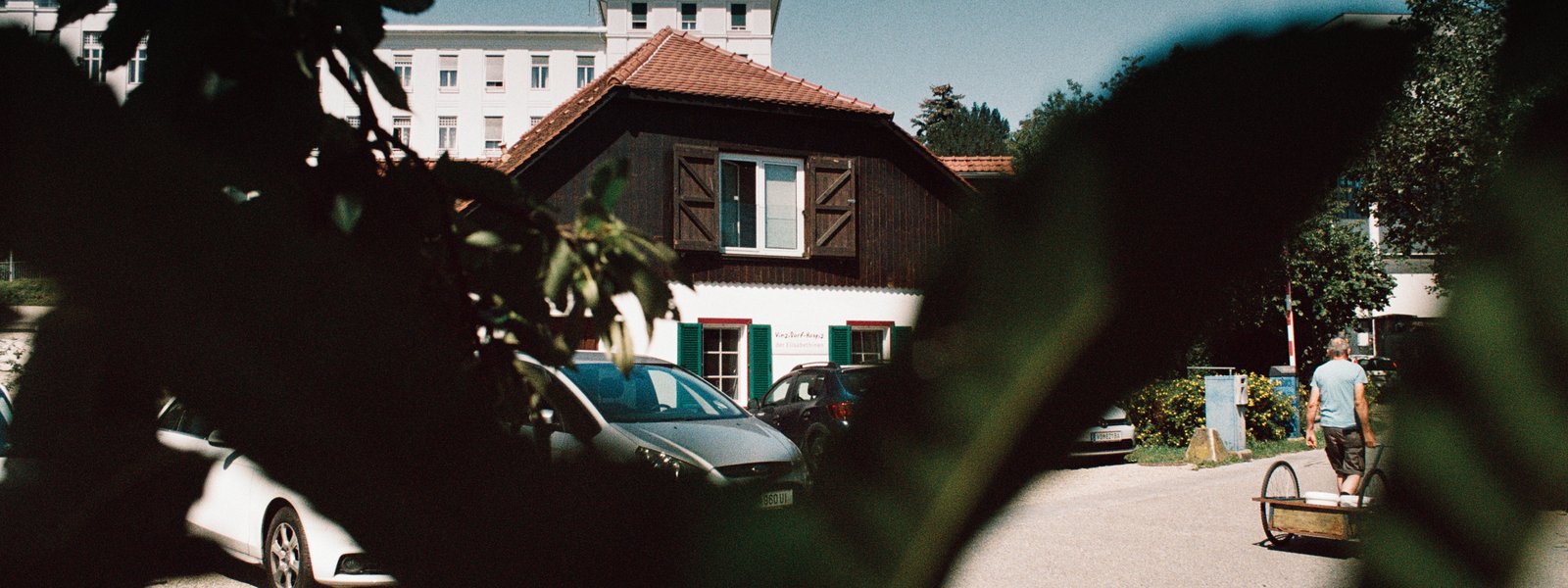 Außensansicht des VinziDorf-Hospizes mit grünen Blättern im Vordergrund